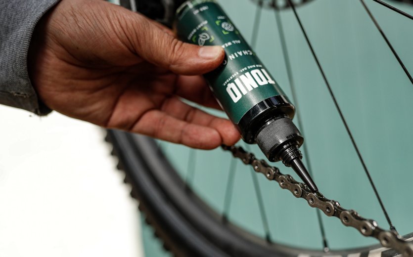De l'huile pour chaîne TONIQ est appliquée sur une chaîne de vélo. 