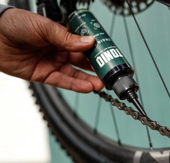 De l'huile pour chaîne TONIQ est appliquée sur une chaîne de vélo. 
