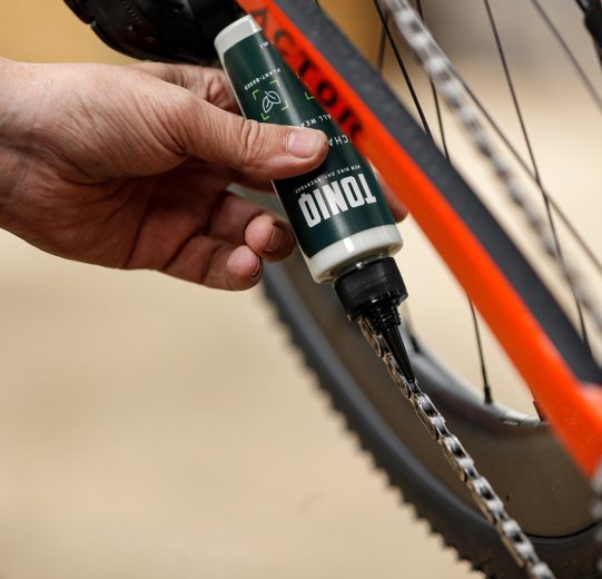De la cire pour chaîne TONIQ est appliquée sur une chaîne de vélo. 