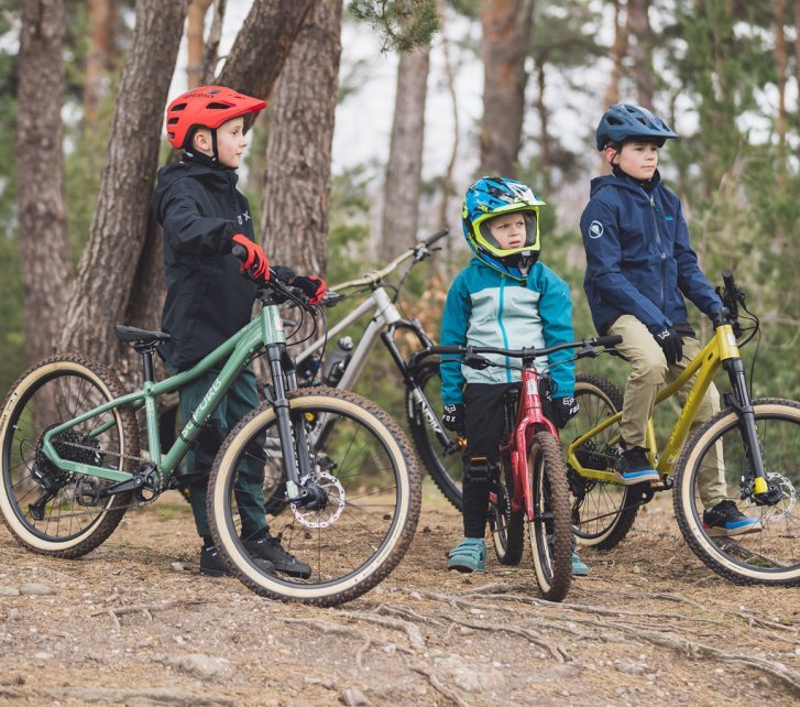 Tres niños en bicis de montaña SUPURB en el bosque.
