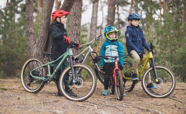 Tres niños en bicis de montaña SUPURB en el bosque.