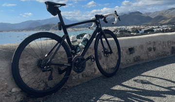 A Specialized Tarmac SL 7 stands leaning against a wall on a coastal road in Mallorca.