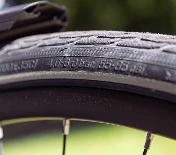 Close-up photo of a bicycle tyre sidewall. The permitted pressure range is in focus.