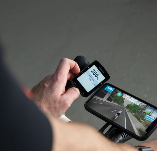 A Garmin Edge bike computer displays performance data in watts during a Zwift workout.