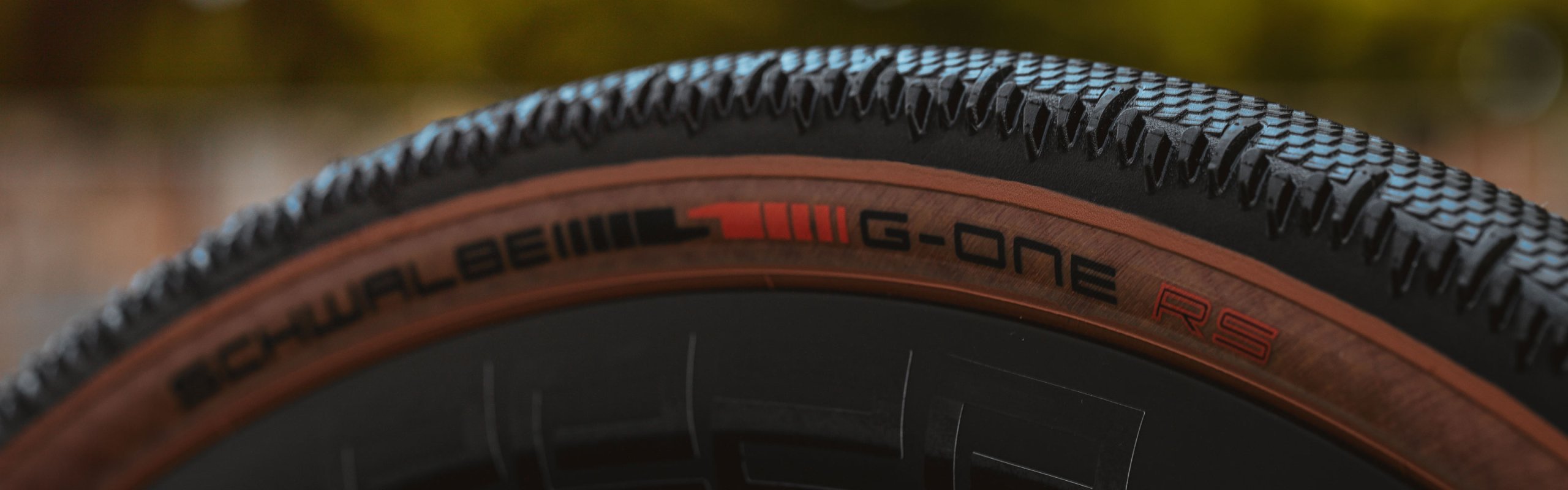 Primer plano del neumático gravel Schwalbe G-One RS con flanco marrón, banda de rodadura rápida y rueda de bicicleta para un alto rendimiento en gravel.