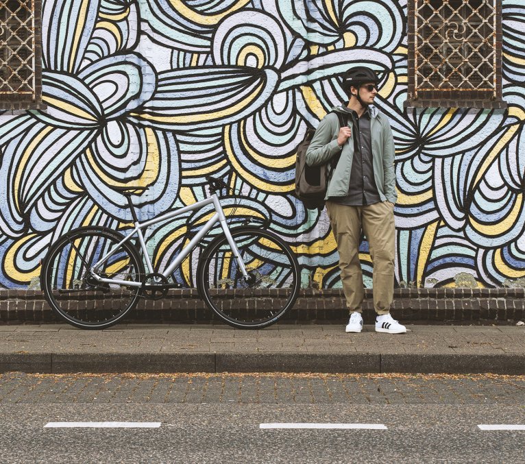 Fahrrad Pendler steht vor einer auffälligen Grafittiwand in urbaner Umgebung