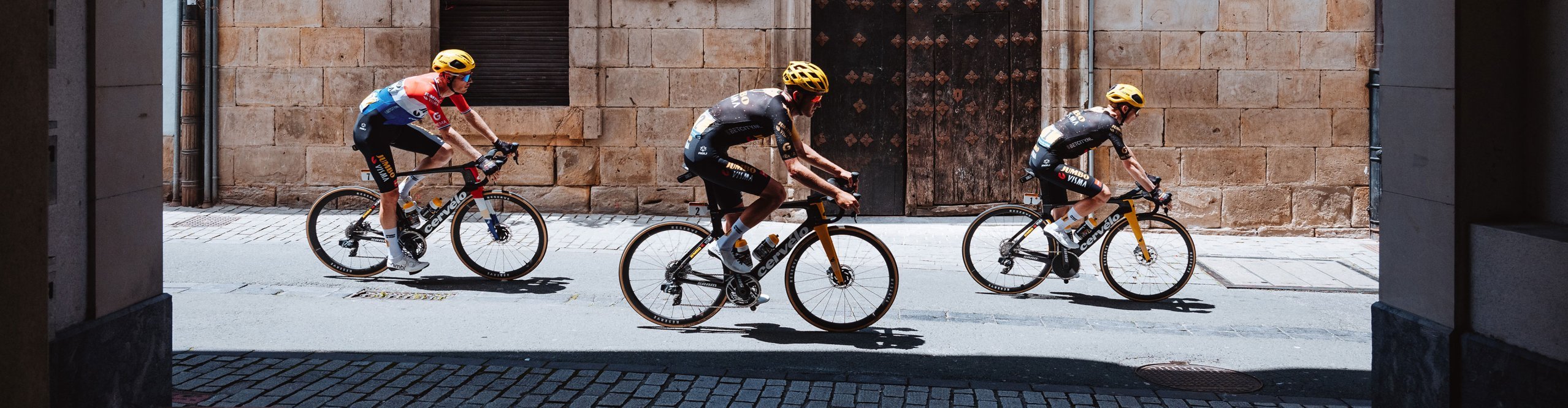 Cervelo Rennradfahrer Trio auf der Straße zwischen Häusern, Tour de France Setting