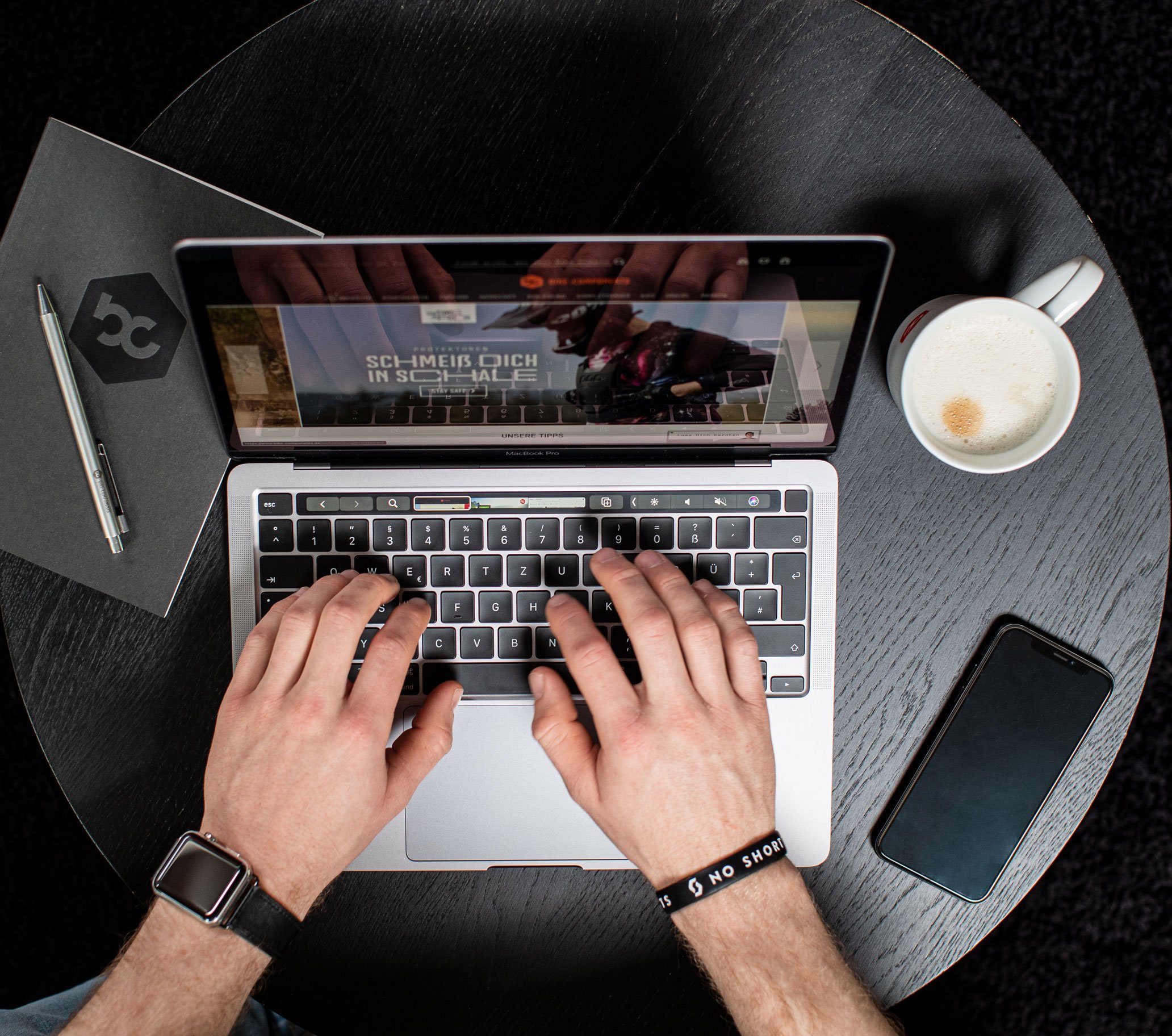 Person erstellt bike-components Blogbeitrag am Laptop und nutzt Smartphone für Recherche