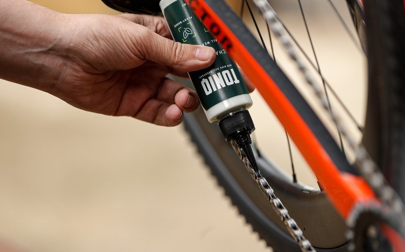 De la cire pour chaîne TONIQ est appliquée sur une chaîne de vélo. 