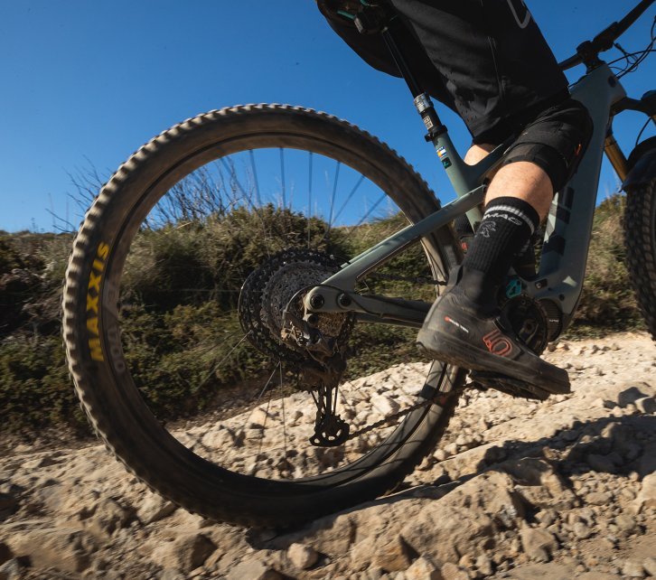 Pictured is the rear triangle of a YETI e-mountain bike while riding over stony ground. 