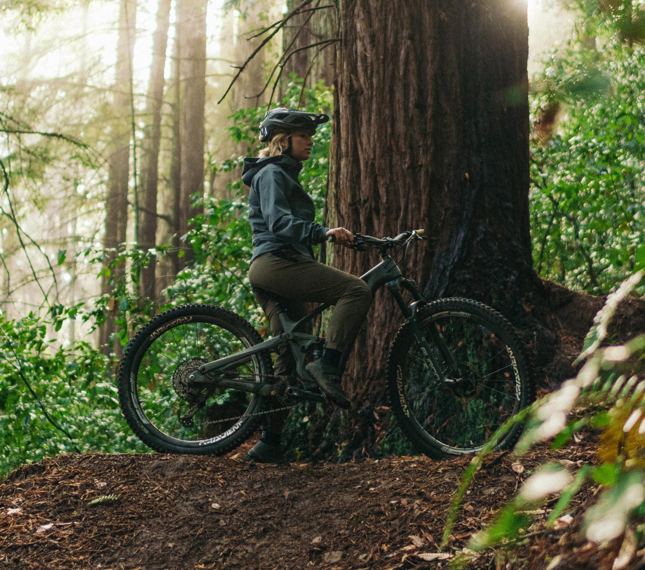 MTB-Fahrerin im FOX Bekleidungs-Set macht Pause am Trail im dichten Wald