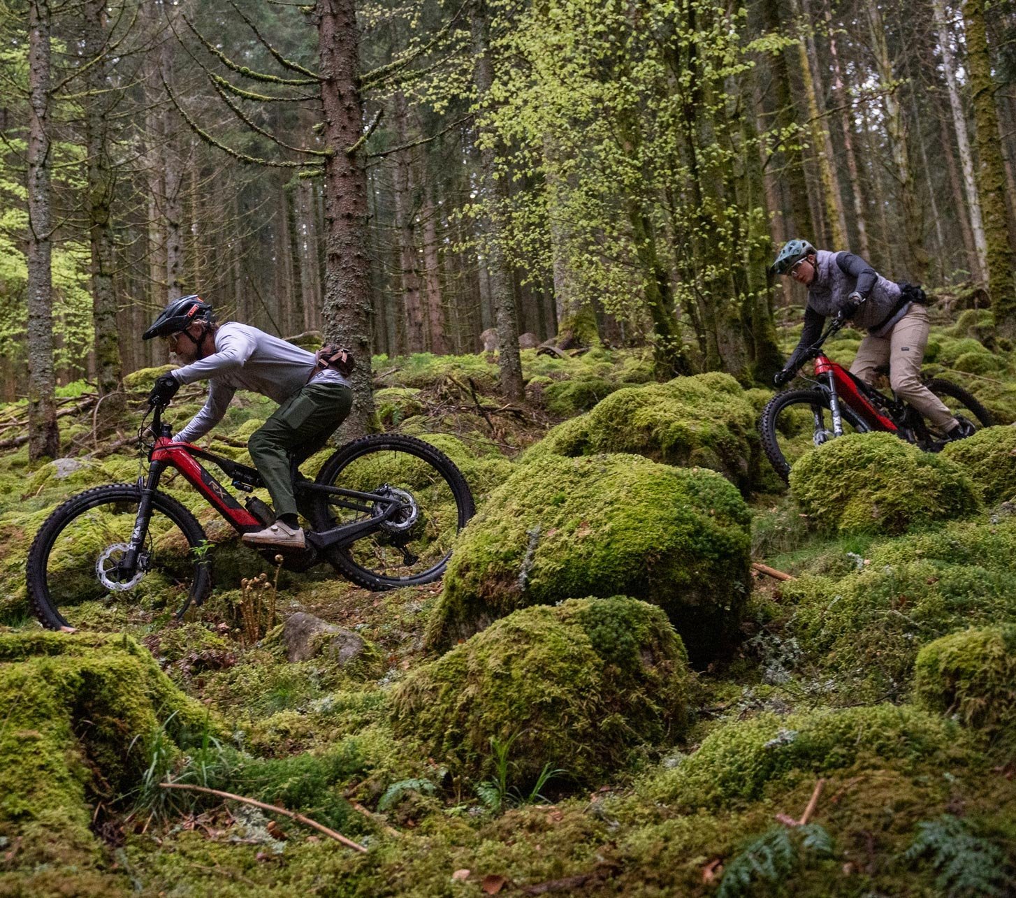 Deux pilotes sur le ROTWILD RX735 Pro e-MTB avec moteur DJI Avinox sur un sentier technique en forêt entre des rochers couverts de mousse