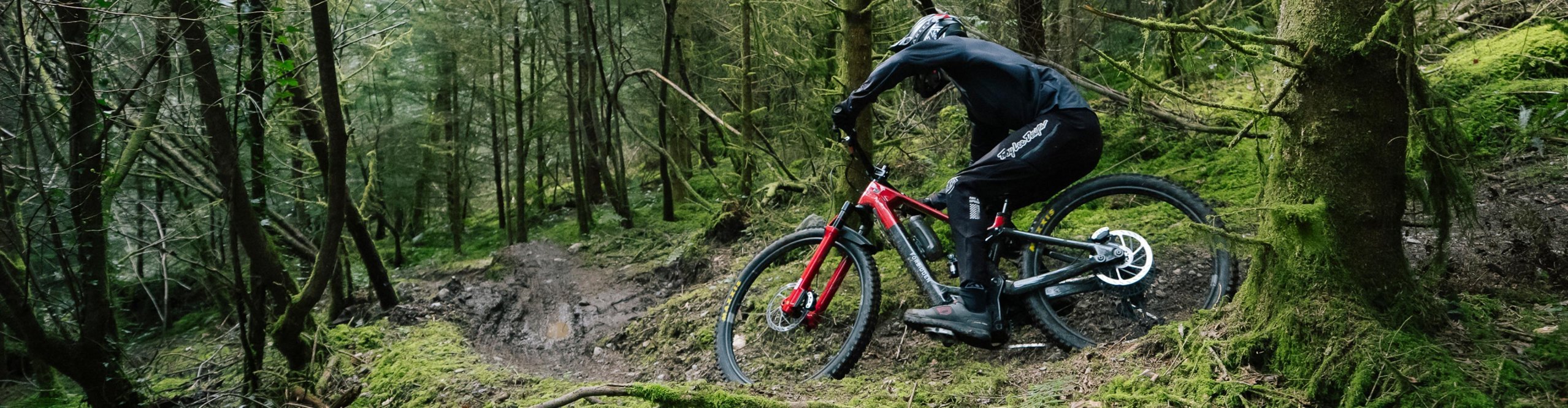Mountain biker rides a Dreadnought e-mountain bike on a technical forest trail.