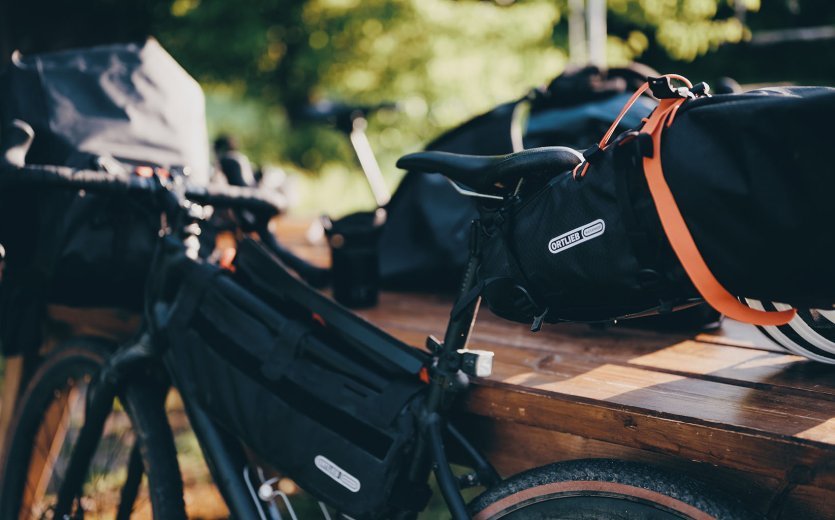 La photo montre un vélo de gravel équipé des sacoches de cadre et de selle d'Ortlieb.