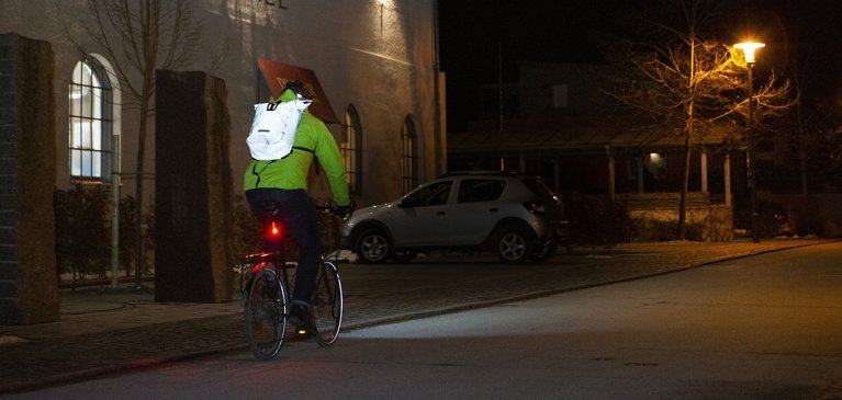Fahrradfahrer mit reflektierendem Rucksack im Straßenverkehr