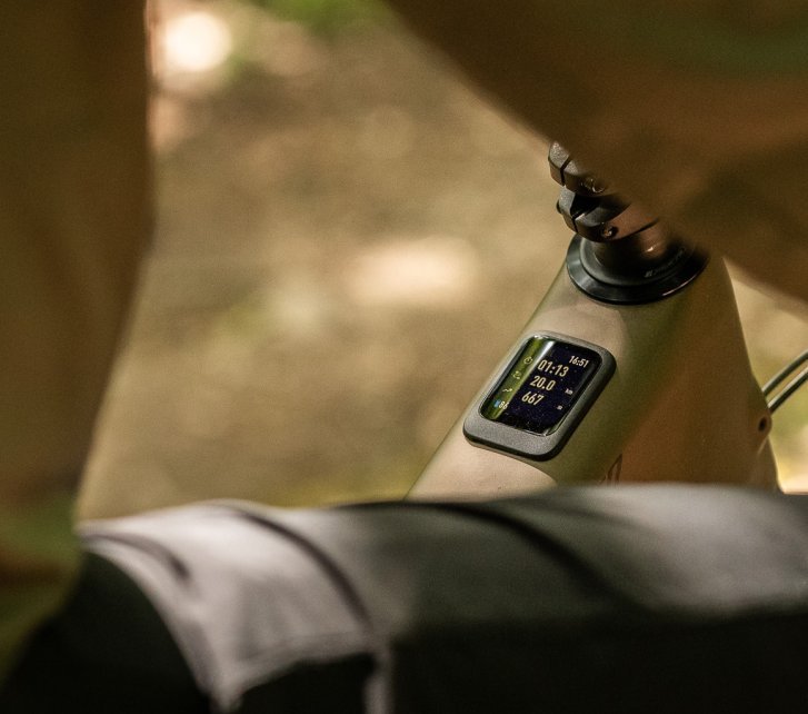 Das Display eines Specialized Turbo Levo 4 E-MTB von schräg hinten fotografiert. Wir sehen unscharf im Vordergrund Bauch, Oberschenkel und Oberarm des Fahrers, die das Bild einzurahmen scheinen. 