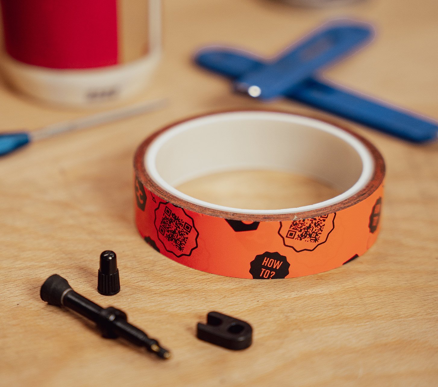 BC Basic Felgenband und Tubeless Montagezubehör auf Holztisch, darunter Ventil und Werkzeug, vorbereitet für die Umrüstung eines Fahrrads auf Tubeless.