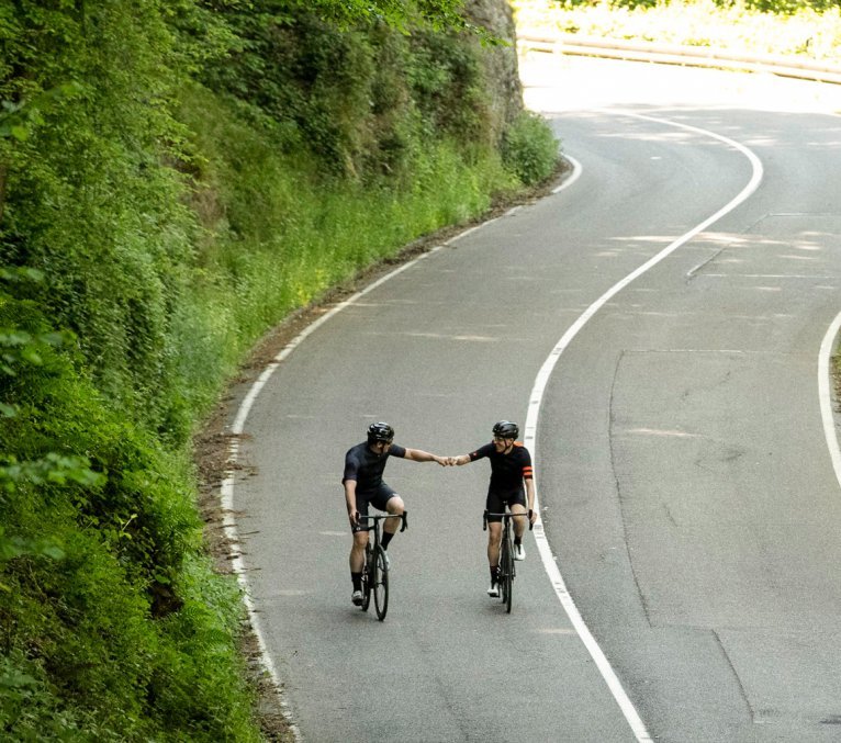 Zwei Rennradfahrer auf Specialized Tarmac SL7 Bikes geben sich nach bewältigter Steigung eine anerkennende Faust.