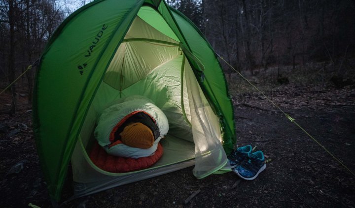 Svenja aus dem bc Produkt Management liegt warm eingepackt in ihrem Deuter Schlafsack in einem VAUDE Zelt.