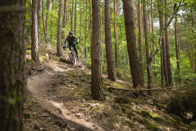 Berno fetzt auf einem Turbo Levo 4 E-MTB durch den Wald auf die Kamera zu.