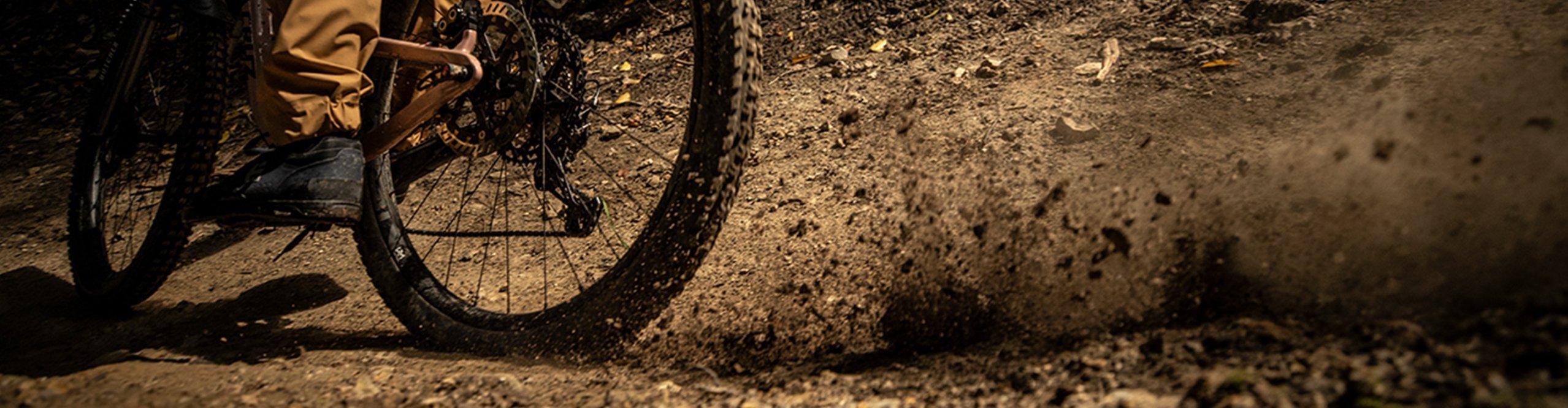 Mountainbiker schleudert mit seinem Hinterreifen Dreck in die Höhe.