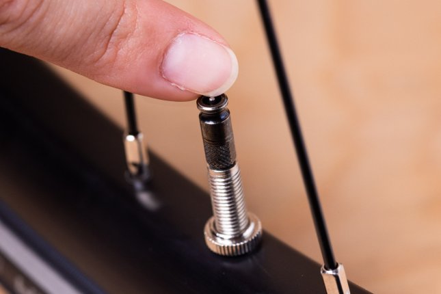 The edge of a fingernail is used to press down the pin inside a Clik Valve to release air.
