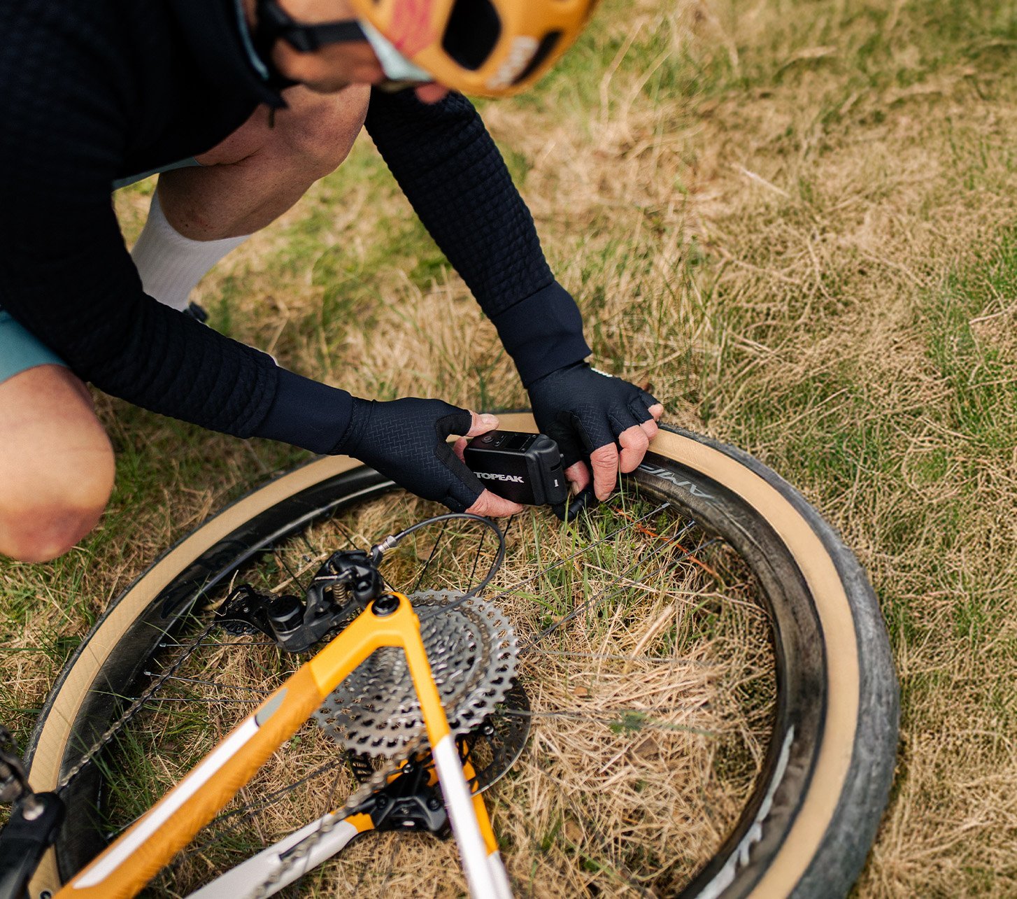 Radfahrer repariert Fahrradreifen mit einer Topeak Minipumpe unterwegs – schnelles Aufpumpen bei Panne auf Gravel- oder Rennradtour.