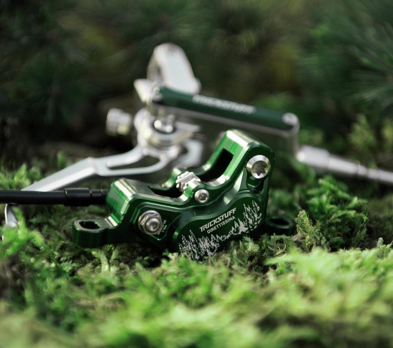Freno de disco Trickstuff Direttissima Forest Green con pinza verde sobre musgo en el bosque