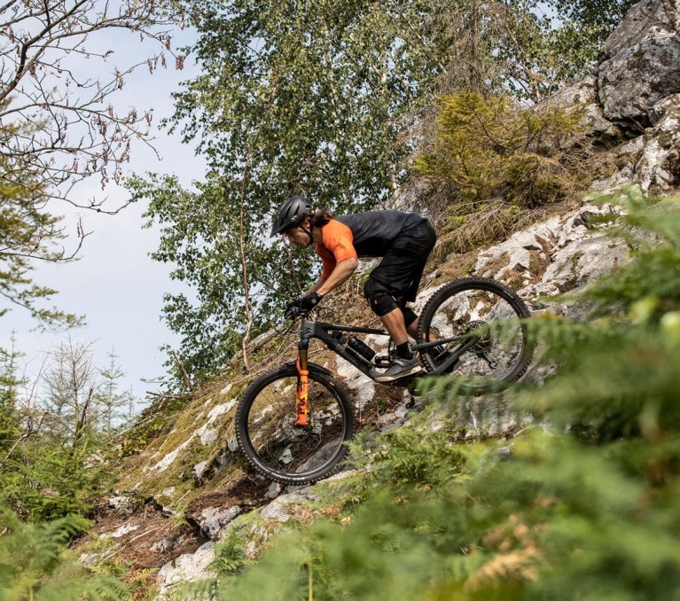 Christian aus dem bc Produktmanagement fährt auf felsigem Untergrund auf einem Santa Cruz Fully Mountainbike bergab.