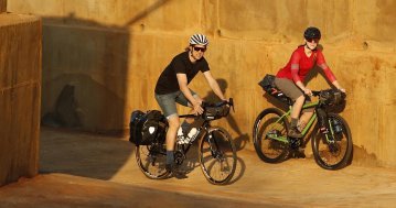 Mann und Frau bei einer Radtour mit Gepäck auf La Palma vor einer sandfarbenen Wand