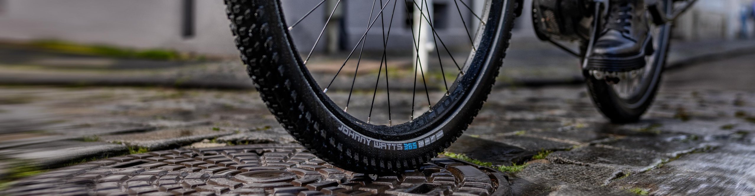 Gros plan du pneu Schwalbe Johnny Watts 365 pour vélo électrique sur pavés mouillés – pneu polyvalent toutes saisons pour e-bike urbain avec adhérence et protection anti-crevaison