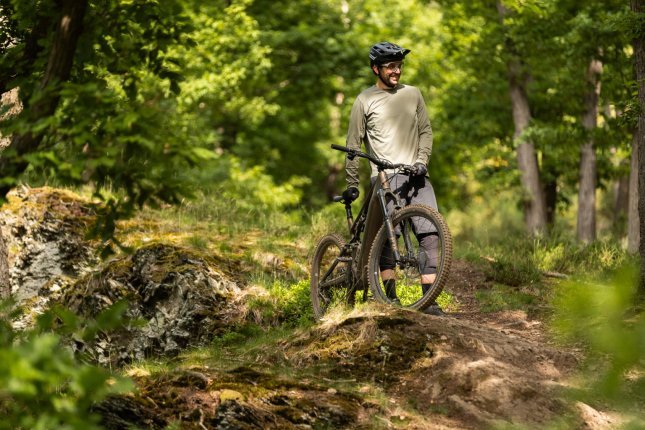 Berno steht mit dem Turbo Levo 4 im Wald und sieht aus, als wäre er glücklich.