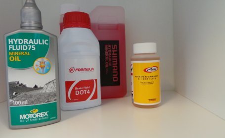 Verschiedene Flaschen mit Bremsflüssigkeit für Fahrräder stehen auf einem Regal