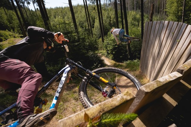 Actionfoto zweier bc Mitarbeiter, die auf ihren Mountainbikes einen Wallride in einem Bikepark fahren