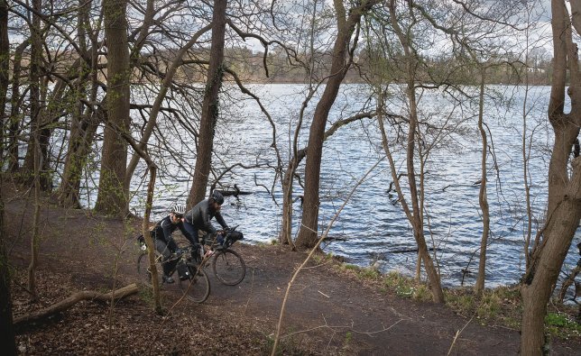 Christian und Marcel radeln über einen Uferweg entlang der Elbe.