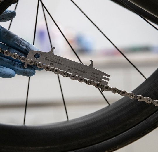 Mit einer Kettenverschleißlehre wird der Zustand einer Rennrad-Kette ermittelt. 