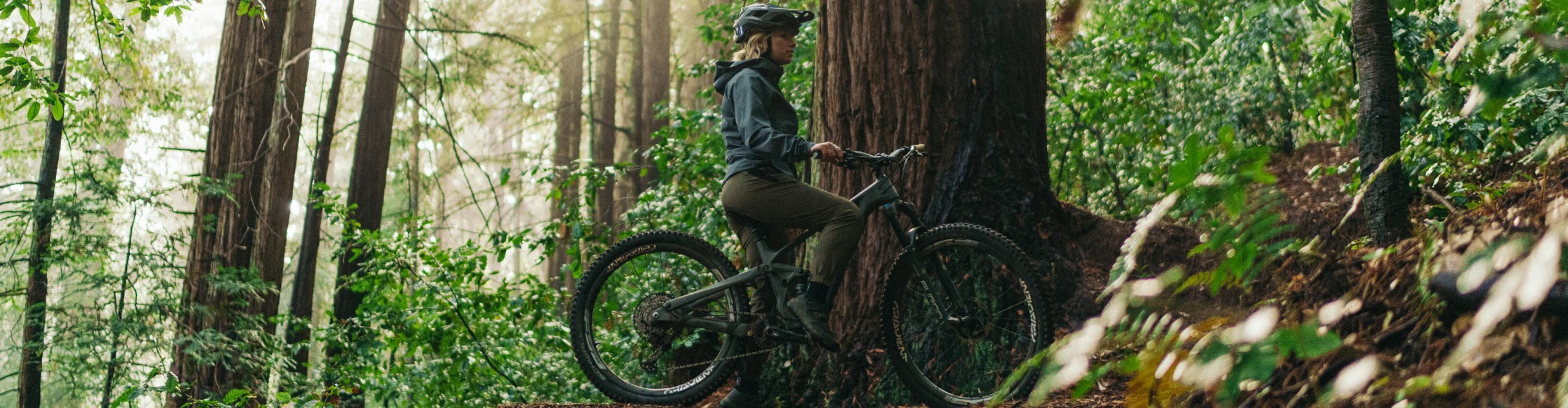 MTB-Fahrerin im FOX Bekleidungs-Set macht Pause am Trail im dichten Wald