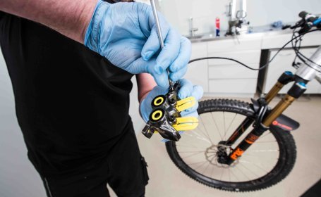 Die kleine Entlüftungsschraube am Bremszylinder einer hydraulischen Scheibenbremse an einem Fahrrad wird entfernt.