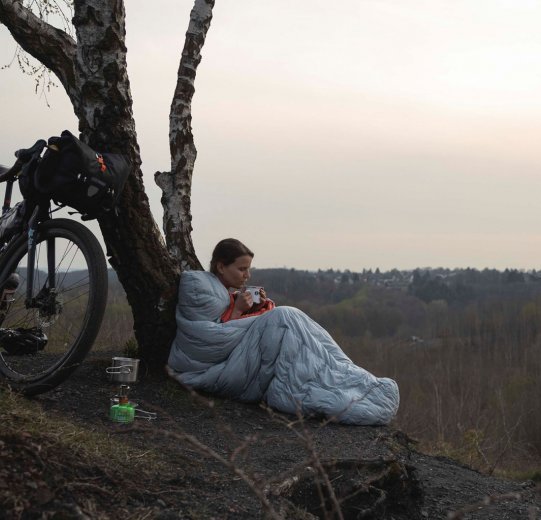 Christian, du service clientèle de bc, replie son matelas de camping. Au premier plan se trouve sa tente, à l'arrière-plan son vélo.