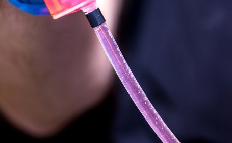 Ein Spritzenschlauch mit einer klaren Flüssigkeit zeigt Luftblasen, die nach oben steigen.