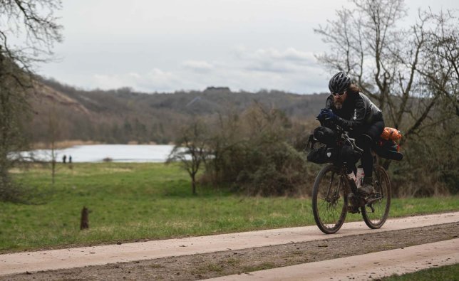 Christian radelt auf dem Auflieger am Ufer der Elbe.