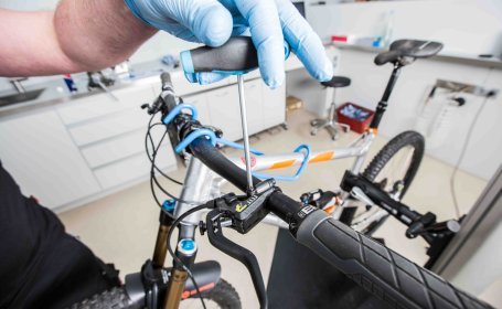 Bild zeigt eine Werkstatt: Die Entlüftungsschraube am Geberkolben einer hydraulischen Fahrradbremse wird wieder eingeschraubt