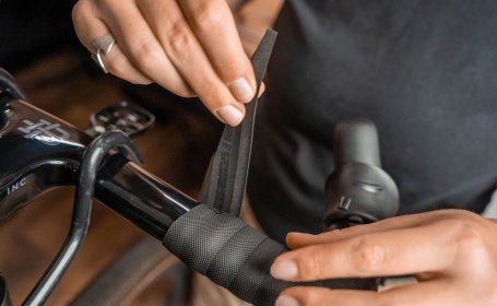 Die Mechanikerin wickelt das Lenkerband zu Ende.