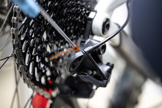From above, the bc mechanic adjusts the B-screw using an Allen key.