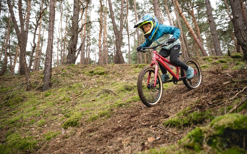 Ein Kind fährt mit dem SUPURB BO20 einen Trail im Wald