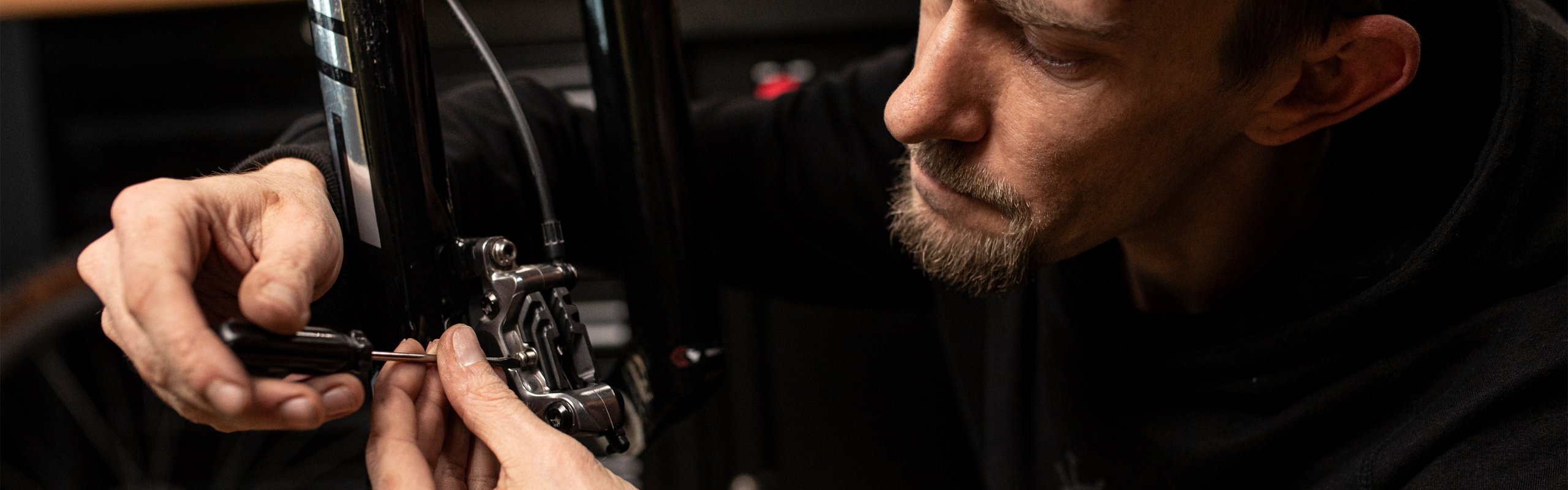 Zweiradmechaniker schraubt an einem Bremssattel