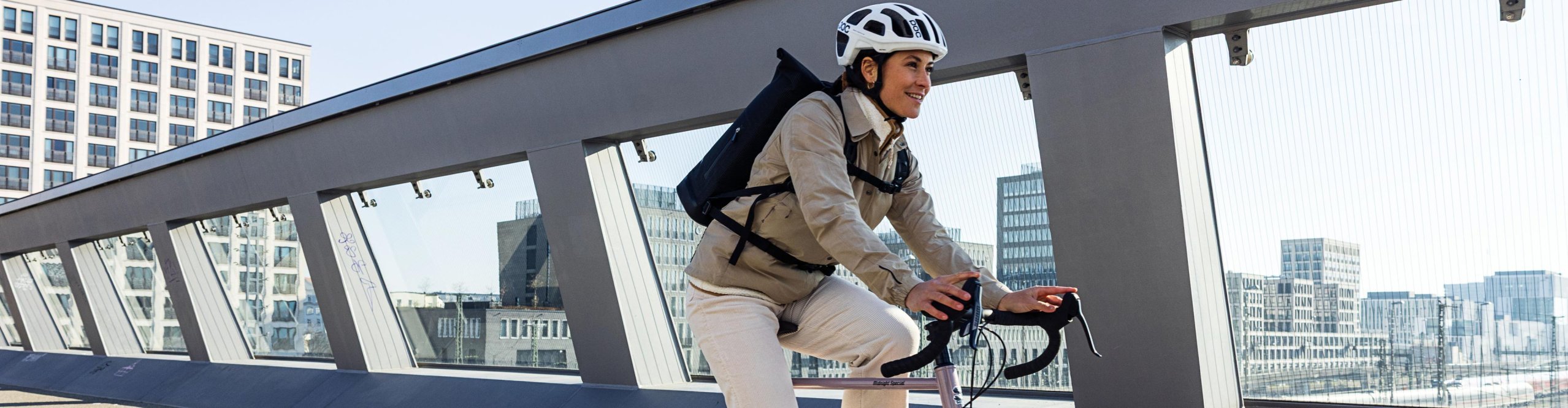 Cycliste avec sac à dos Ortlieb et casque roulant sur une piste cyclable dans une ville moderne