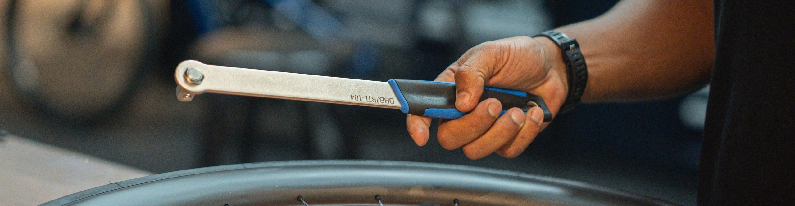BBB Fahrradwerkzeug in der Hand eines Mechanikers über einem Laufrad mit Kassette in der Fahrradwerkstatt.