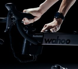 Close-up: Two male hands adjust the reach on a Wahoo smart bike.