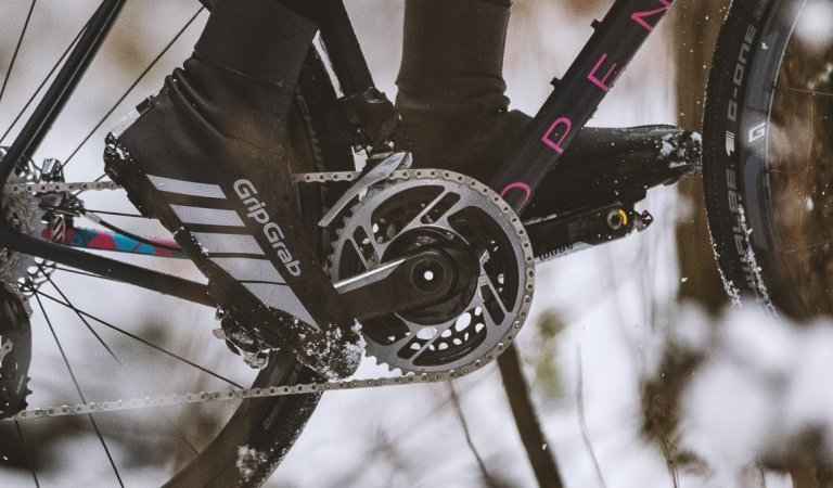 Detail shot of feet pedaling a bike in a snowy landscape.